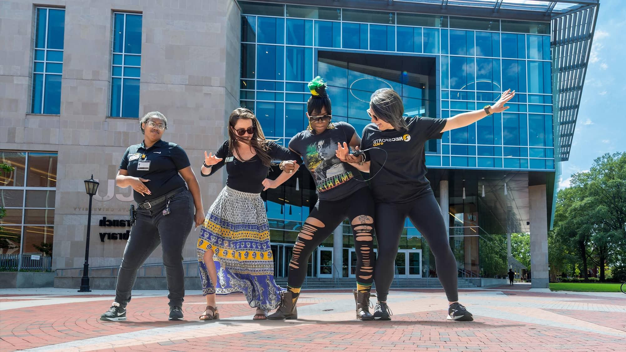 Four female VCU students standing arm-in-arm in from of Cabell Library